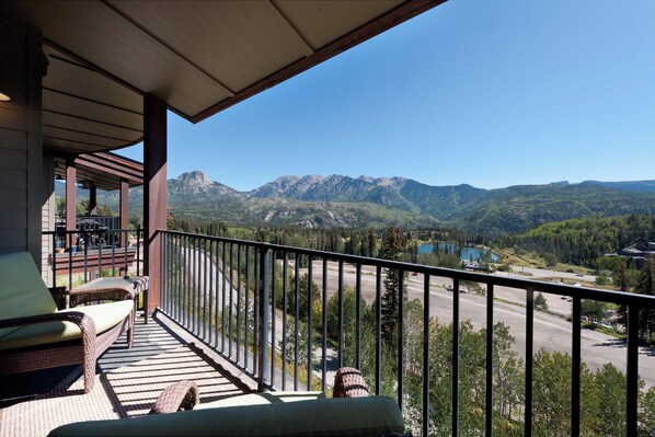 A balcony with wicker furniture, a view of mountains, and a lake. - Peregrine Point Condo Steps to Lifts - AC/Amazing Views (Durango)