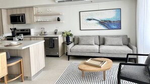 A modern kitchen with a central island, a grey sofa, and a coffee table. - J-pacp506 3 Bedroom Condo (Jacó)