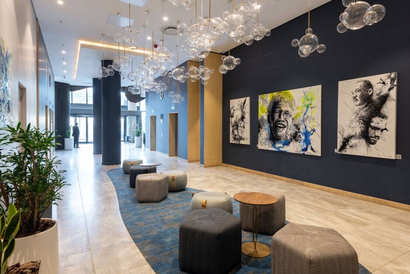 Un vestíbulo moderno con alfombra azul, asientos redondos y arte abstracto en las paredes.