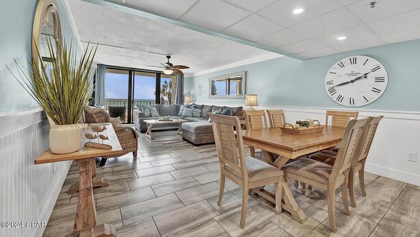 A spacious living room with a large sofa, a dining table with chairs, and a ceiling fan. - Edgewater Tower 3-104 (Panama City Beach)