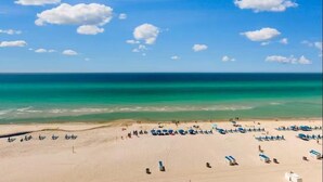 A beach with clear turquoise waters, a sandy shore, and several blue umbrellas. - Splash 507e (Panama City Beach)