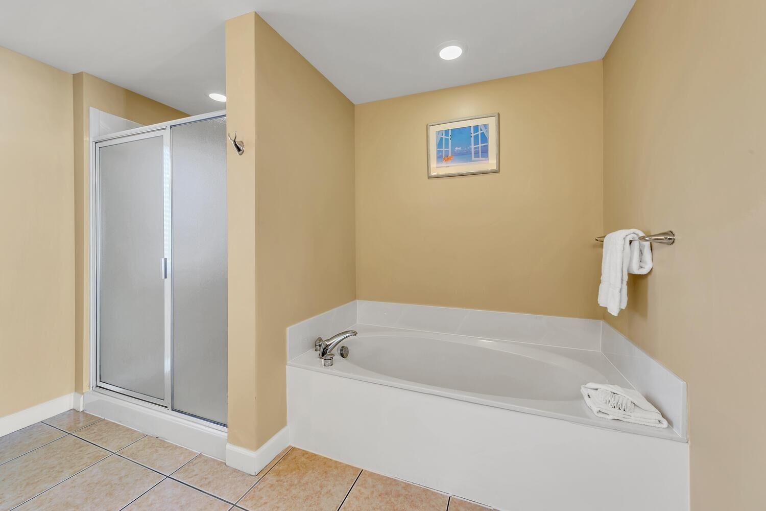 A bathroom with a walk-in shower, a bathtub, and a towel rack.