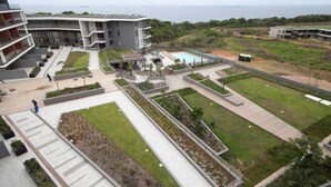 Un bâtiment moderne doté d’une piscine, d’espaces verts et offrant une vue sur la mer.