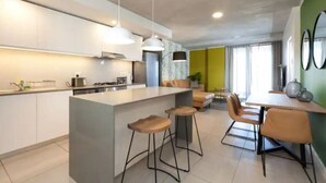 Une cuisine moderne dotée d’un îlot central, de tabourets de bar et d’un coin repas avec une table et des chaises.