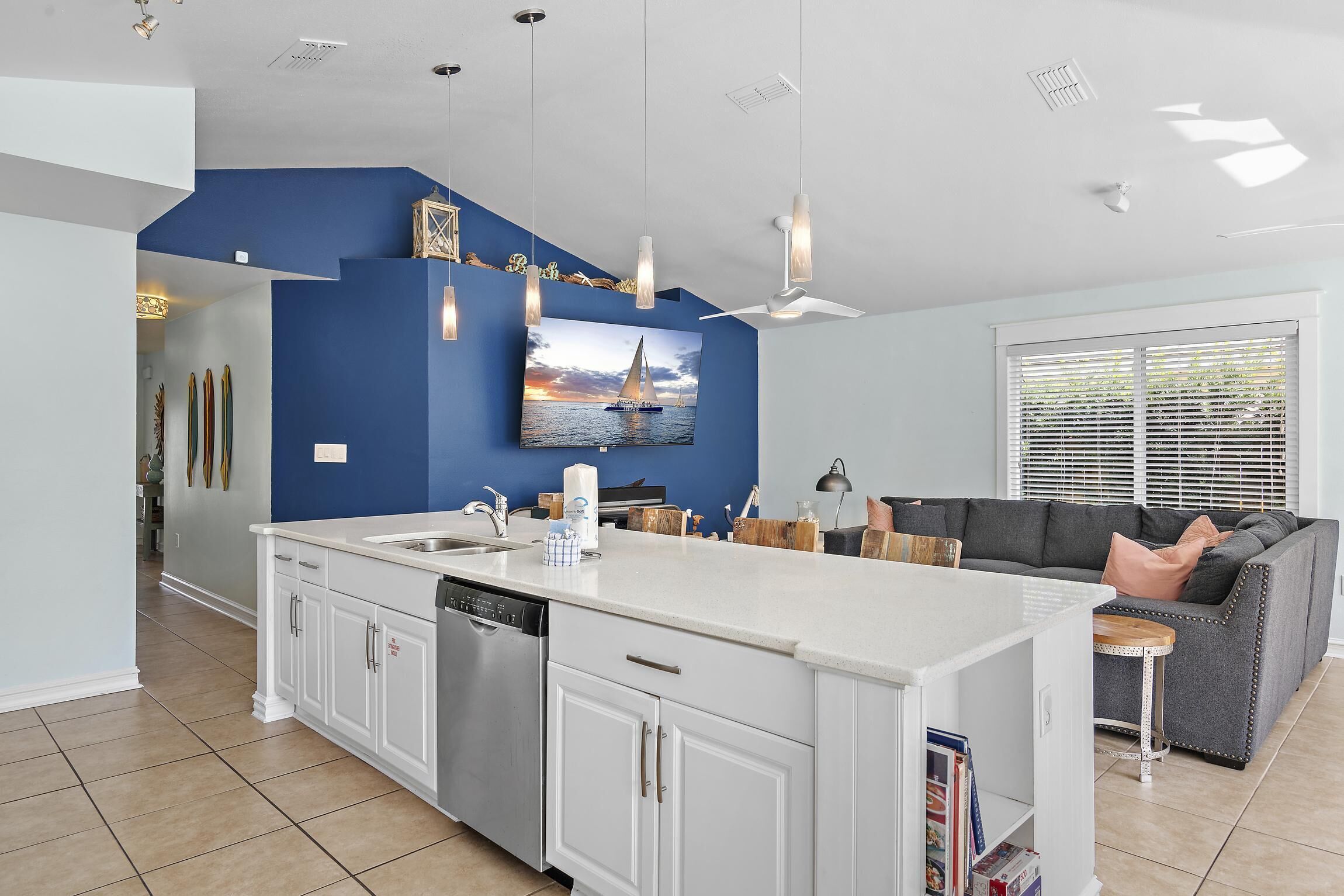 Een moderne keuken met witte kasten, een groot eiland en een blauwe accentmuur.