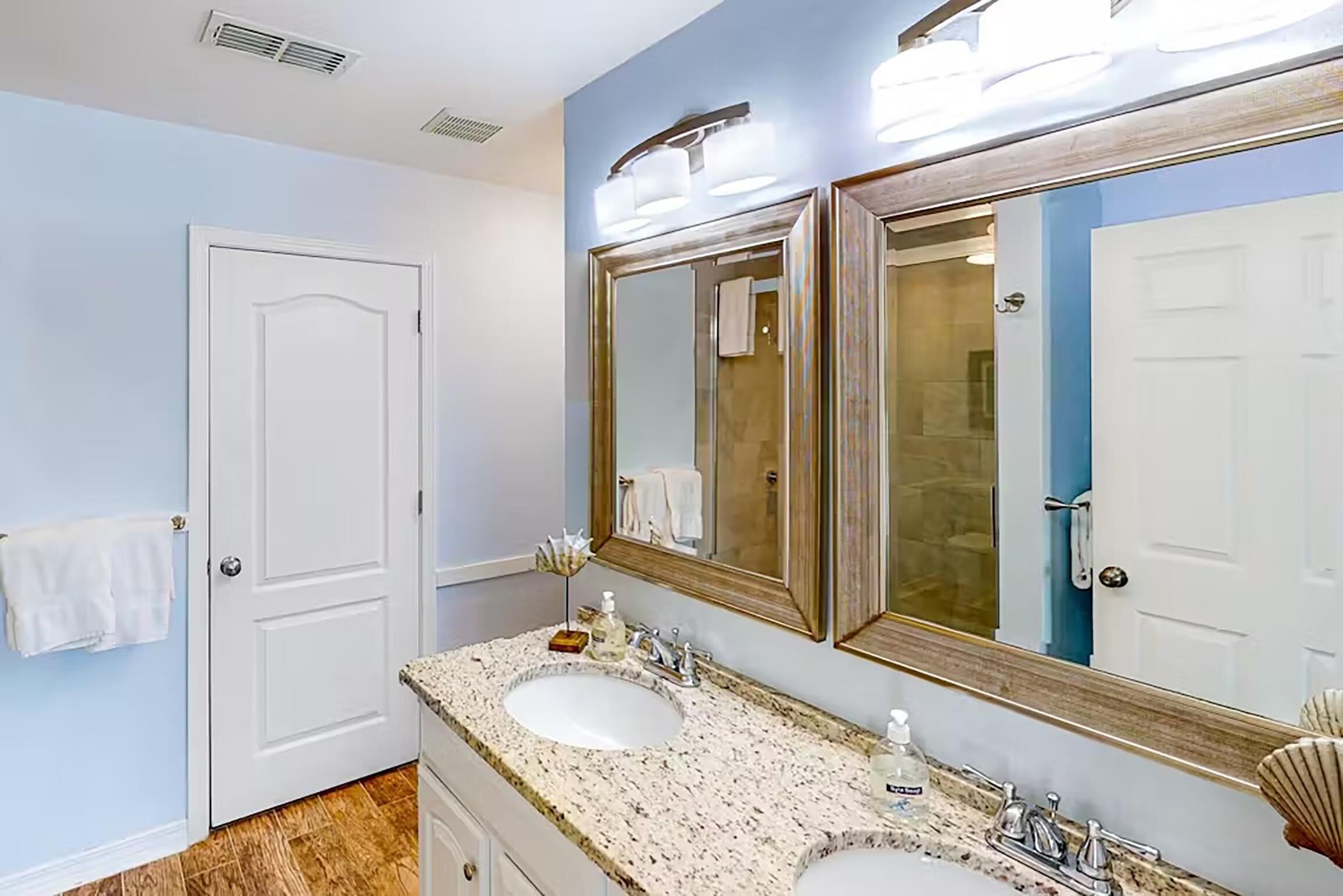A bathroom with two sinks, a large mirror, and a towel rack.