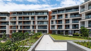A modern multi-story residential building with balconies, a central courtyard, and landscaped gardens. - Coral Point Executive Studio Apartment E316 (Sibaya Precinct)