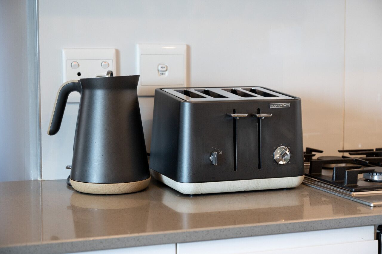 Une cuisine équipée d’un grille-pain moderne et d’une bouilloire posés sur le plan de travail.