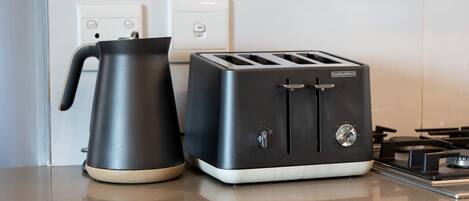 Une cuisine équipée d’un grille-pain moderne et d’une bouilloire posés sur le plan de travail.