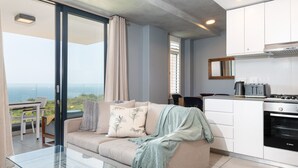 Ein modernes Wohnzimmer mit einer Couch, einem Glastisch und Blick auf den Ozean.