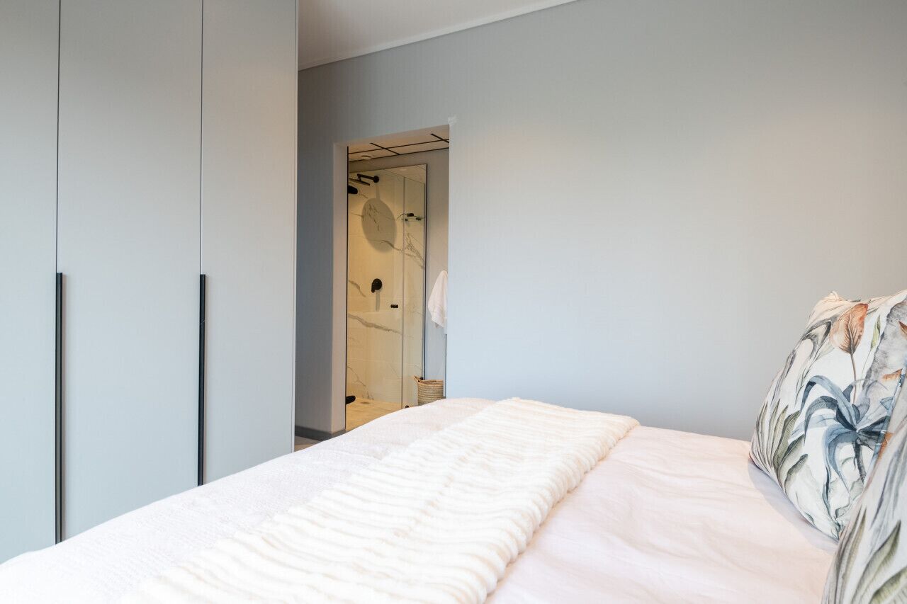 A bedroom with a bed, a wardrobe, and a bathroom visible through an open door.