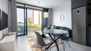 A modern kitchen with a glass dining table, grey upholstered chairs, and a built-in stainless steel refrigerator. - Luxury Bellagio 003 (uMhlanga Ridge, KwaZulu-Natal)