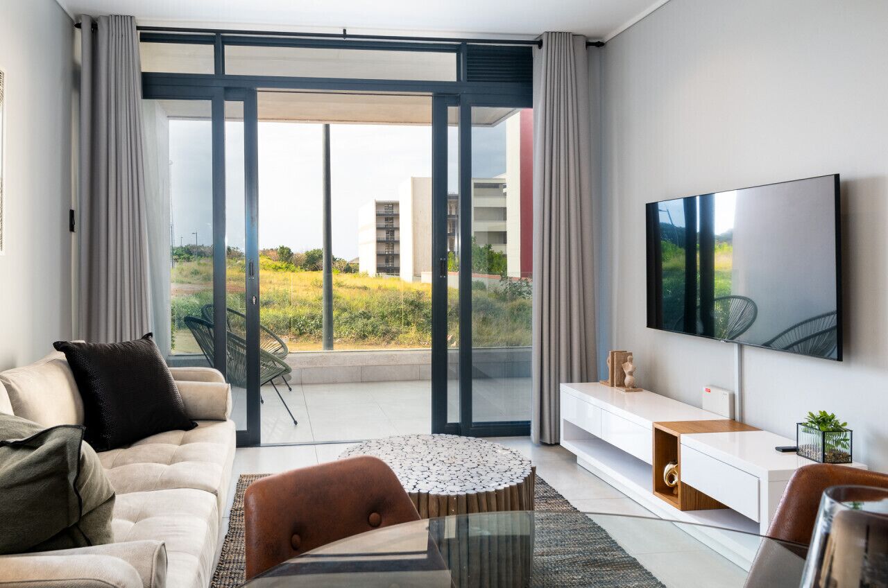 Ein modernes Wohnzimmer mit einer Couch, einem Couchtisch und einem an der Wand befestigten Fernseher.