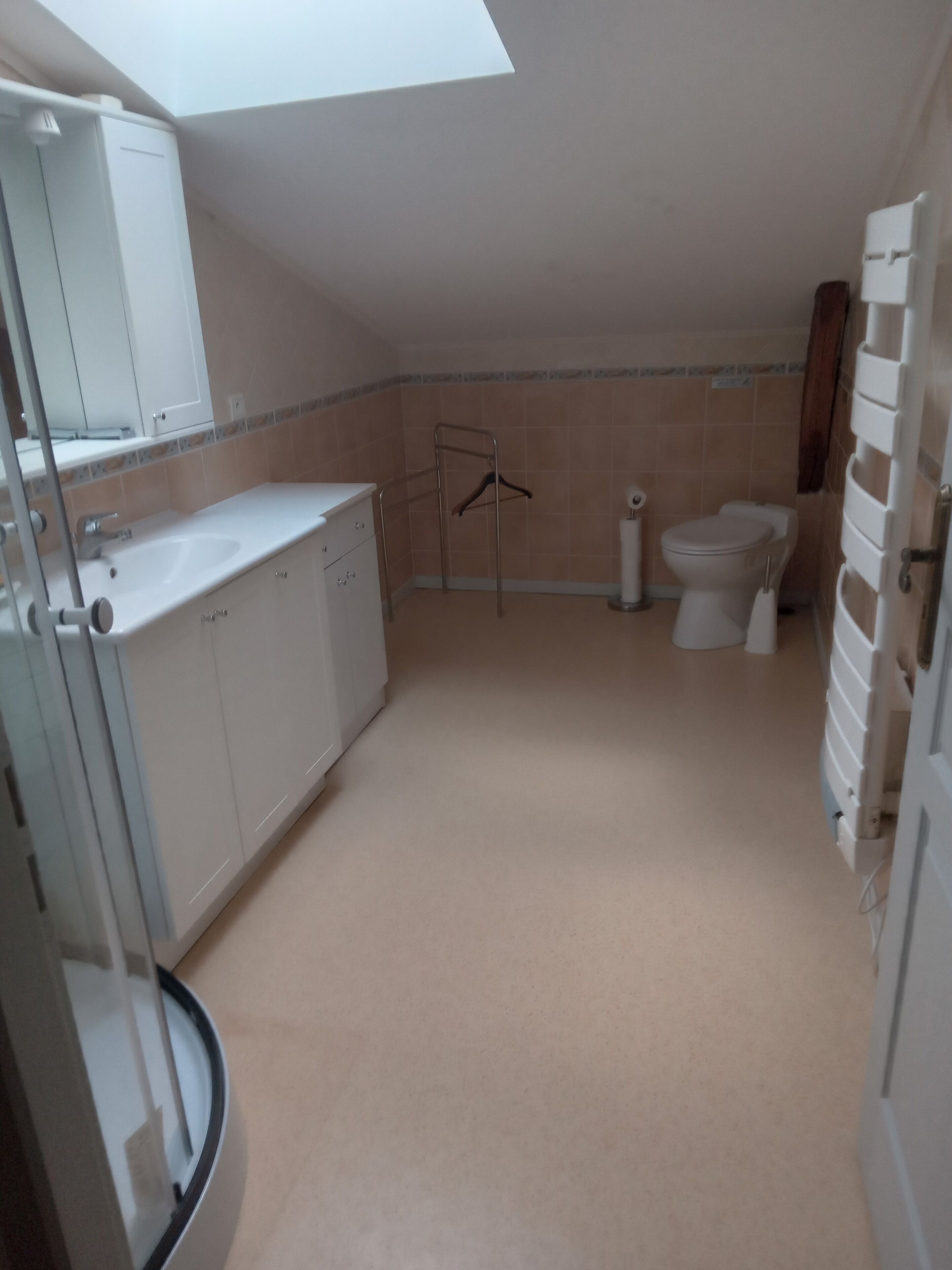 Un baño pequeño y moderno con tragaluz, un lavamanos blanco, inodoro y zona de ducha.