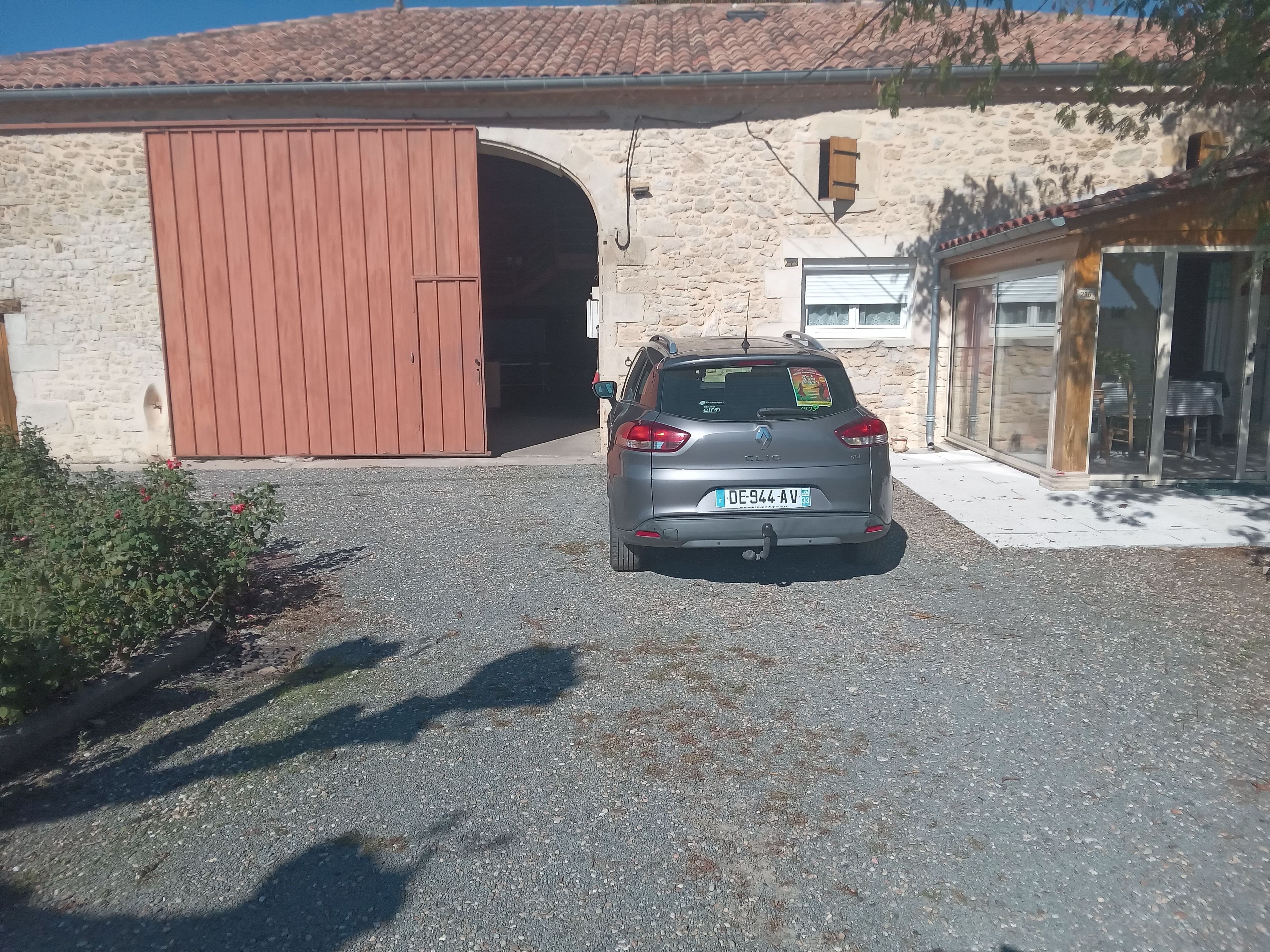 A car parked in front of a building with a stone facade and a large wooden door.