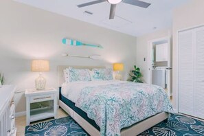 A bedroom with a bed, nightstands, a ceiling fan, and a door.