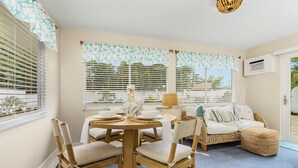 A cozy room with a round table, chairs, a sofa, and a small ottoman.