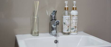 Un lavabo de salle de bain avec un miroir au-dessus, un robinet et deux flacons de crème pour les mains.
