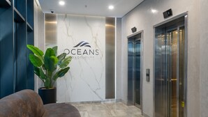 Un hall d’entrée moderne avec un mur en marbre, une plante en pot et un ascenseur.