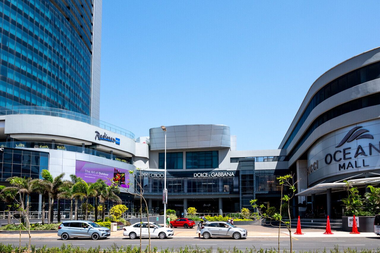 A modern building with a curved facade, featuring the logos of Dolce & Gabbana and Jimmy Choo.