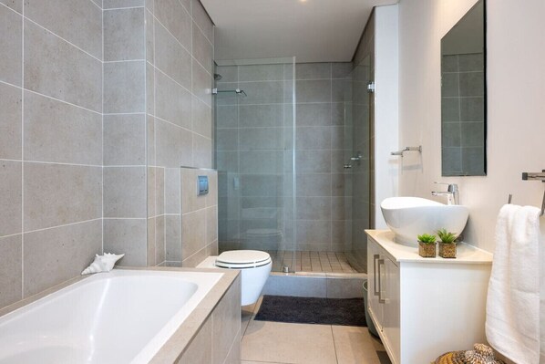 Un baño moderno con bañera, inodoro y zona de ducha.