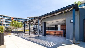 Zona salotto esterna moderna con patio coperto, un bar e una scala che conduce a un livello superiore.