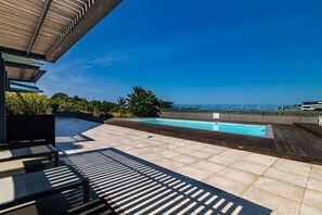 A rooftop pool area with a clear view of the ocean, surrounded by greenery and modern outdoor furniture. - Superb East 311 at Coral Point (Sibaya Precinct, KwaZulu-Natal)