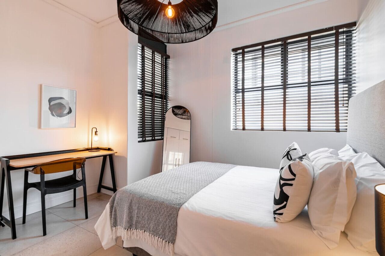 Une chambre à coucher comprenant un lit, une table de chevet, une lampe et un bureau avec une chaise.