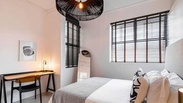 Une chambre à coucher comprenant un lit, une table de chevet, une lampe et un bureau avec une chaise.