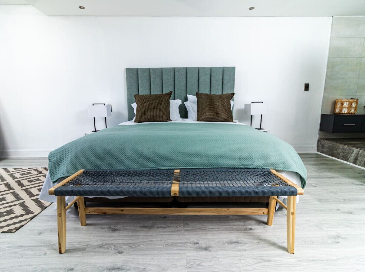 Une chambre moderne avec un lit, un banc, des tables de chevet et un tapis à motifs.