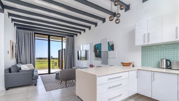 Una cocina moderna con armarios blancos, una isla grande y vistas al exterior.