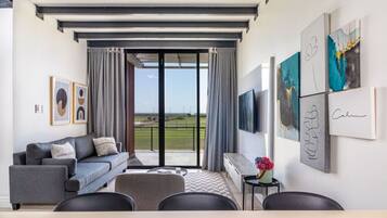 Un salon moderne avec un canapé gris, un téléviseur à écran plat et des œuvres d’art accrochées aux murs.