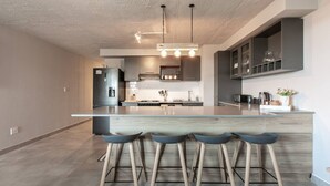 A modern kitchen with a central island, bar stools, and pendant lighting.