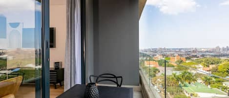 A balcony with a table, chairs, and a vase.