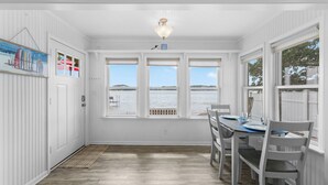 A dining area with a view of the water, white walls, and a ceiling light.