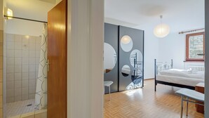 A modern bathroom with a shower, a wooden door, and a tiled floor. - Ca Cornocc With Private Terrace in Gordola (Gordola)