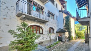 A narrow stone pathway leading to a building with a stone facade, a small tree, and a metal gate. - Ca Cornocc With Private Terrace in Gordola (Gordola)