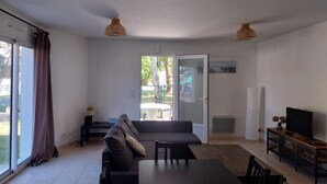 A modern living room with a sofa, dining table, and TV. - WELCOME VILLA (Andernos-les-Bains)