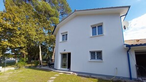 A two-story white building with a flat roof, a satellite dish, and a visible garage door. - WELCOME VILLA (Andernos-les-Bains)