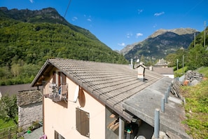 A mountain house with a tiled roof, stone walls, and a balcony overlooking a valley. - Ca Contina (Sonogno)