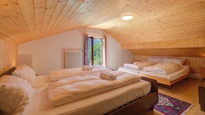 A wooden-paneled room with two beds, a window, and a radiator. - Ca Contina in Val Verzasca (Sonogno)
