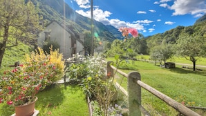 A rural landscape with a house surrounded by lush greenery and flowering plants. - Ca Contina in Val Verzasca (Sonogno)
