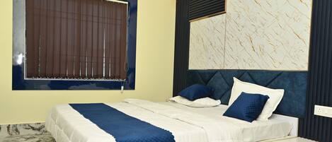 A bedroom with a bed, a nightstand, a wall-mounted lamp, a window with blinds, and a marble-patterned floor.