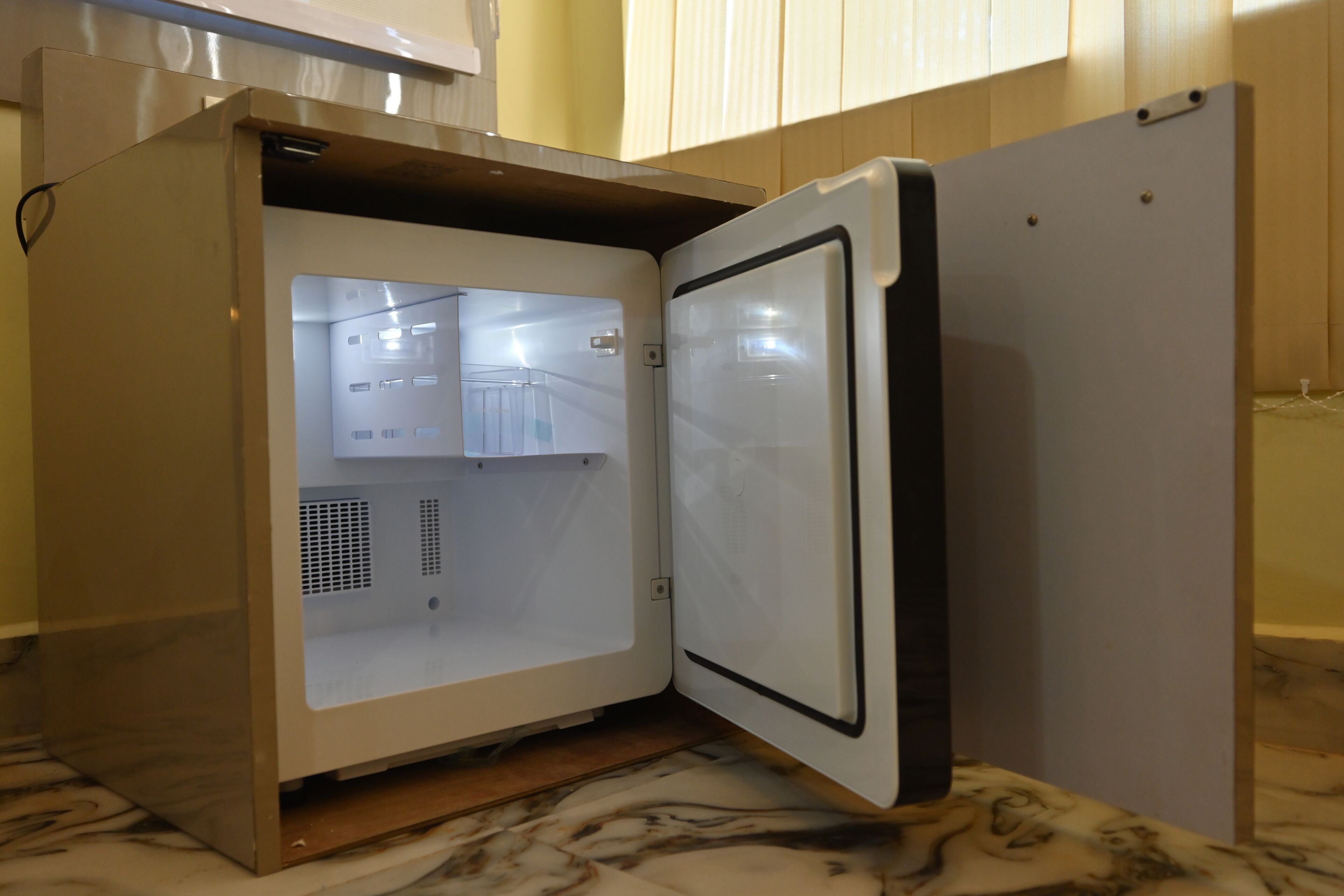 A compact refrigerator with a freezer compartment, a control panel, and a door handle.