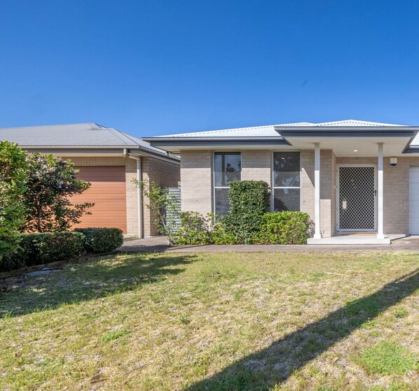 A two-story house with a garage, a front porch, and a small front yard. - Shelly's Bay Escape, 27c Dowling St - stylish with ducted air con and Wi-Fi (Nelson Bay)