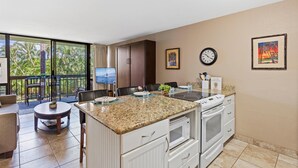 Una cocina moderna con una isla grande, un comedor con vistas y un balcón con mobiliario de exterior.