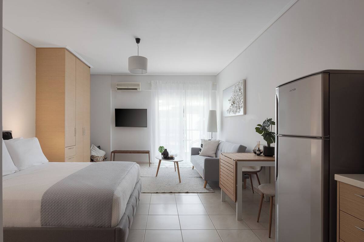 A modern hotel room with a bed, a desk, a refrigerator, and a TV.