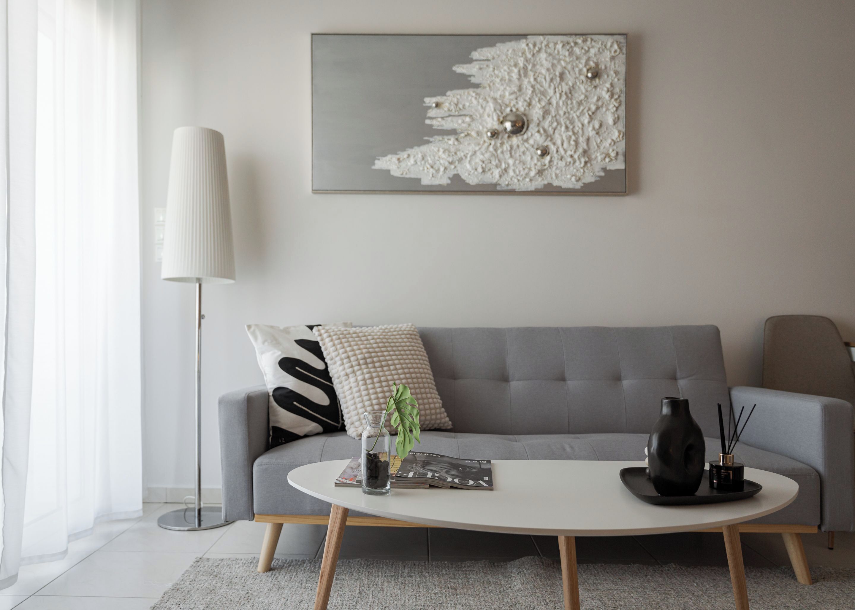 A modern living room with a grey sofa, a white coffee table, and a floor lamp.