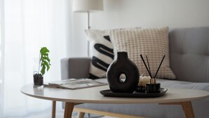 A modern living room with a round coffee table, a potted plant, a decorative vase, candles, and a magazine. - Athenian Comfort Apartments (Zografos)