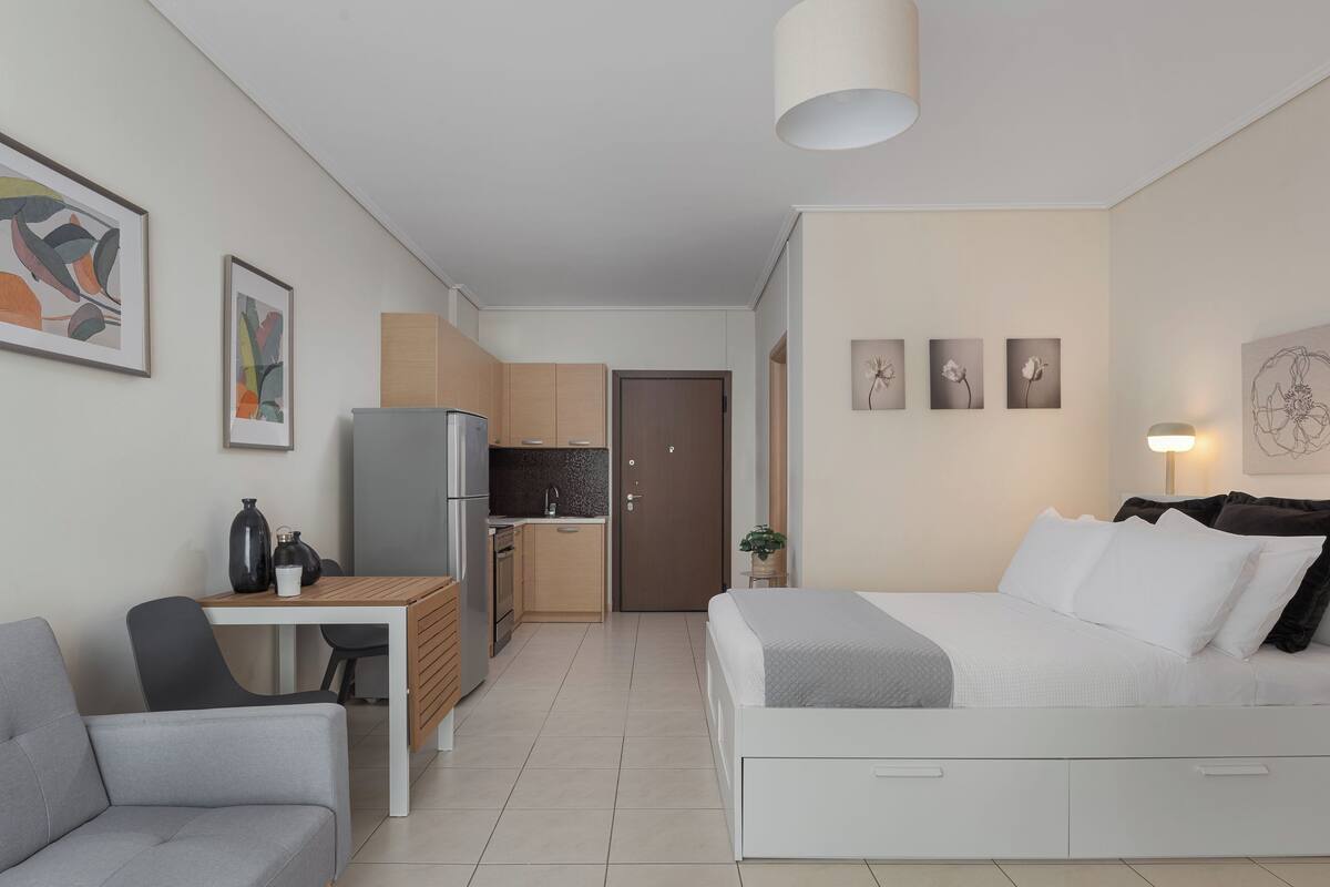 A compact, modern apartment with a kitchenette, a dining area, and a bedroom.